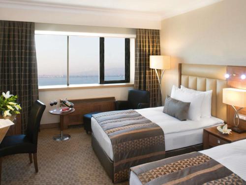 a hotel room with two beds and a window at Mövenpick Hotel Izmir in Izmir