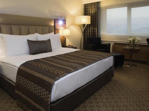 a hotel room with a large bed and a chair at Mövenpick Hotel Izmir in Izmir