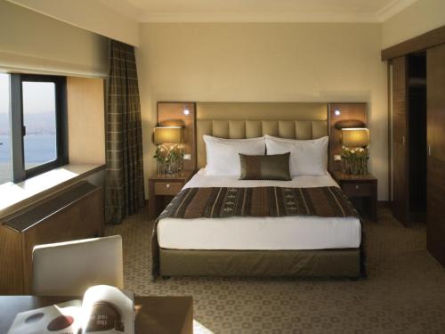 a hotel room with a large bed and a window at Mövenpick Hotel Izmir in Izmir