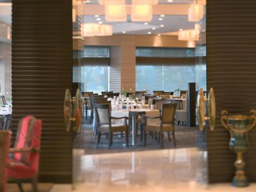 a dining room with tables and chairs in a restaurant at Mövenpick Hotel Izmir in Izmir