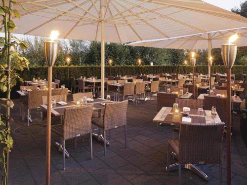 a restaurant with tables and chairs and an umbrella at Mövenpick Hotel Zurich Airport in Glattbrugg