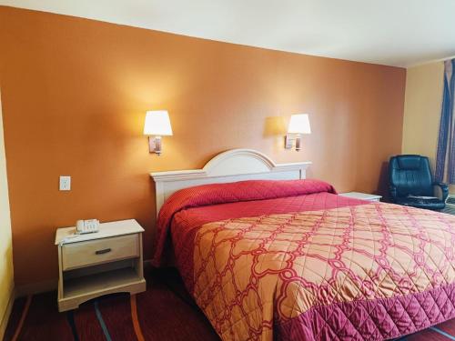 a hotel room with a bed with a red comforter at Heights Inn by Townhouse Harker Heights, TX in Harker Heights