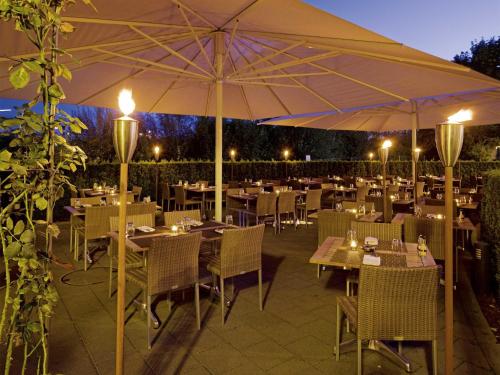 a restaurant with tables and chairs and an umbrella at Mövenpick Hotel Zurich Airport in Glattbrugg