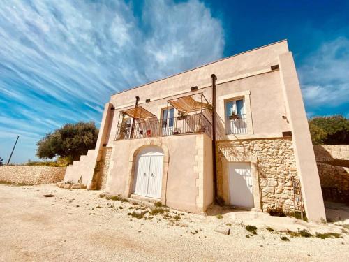a building with a white door and a balcony at Casale Micale in Noto