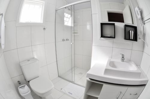 uma casa de banho com um chuveiro, um WC e um lavatório. em Pousada Gramadense em Gramado