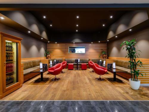 a bar with red chairs and tables in a room at Mövenpick Hotel Egerkingen in Egerkingen