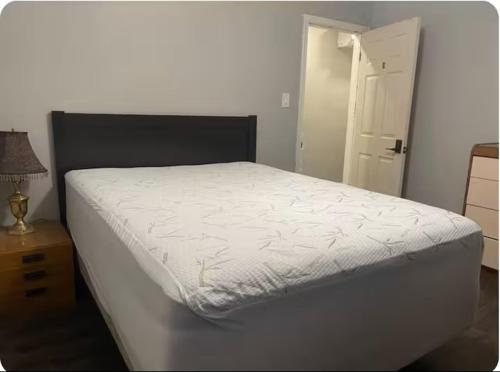 a bedroom with a white bed with a night stand and a door at Bungalow in a Quiet Neighborhood in Waterloo