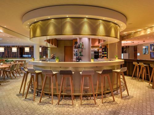 a bar in a restaurant with stools at Mövenpick Hotel Geneva in Geneva