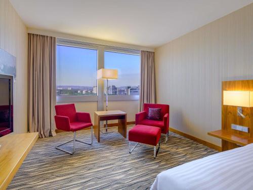a hotel room with two chairs and a table and a bed at Mövenpick Hotel Geneva in Geneva