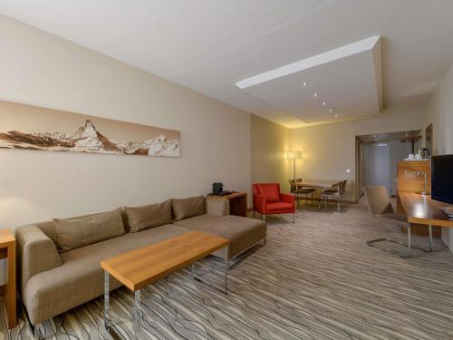 a living room with a couch and a table at Mövenpick Hotel Geneva in Geneva