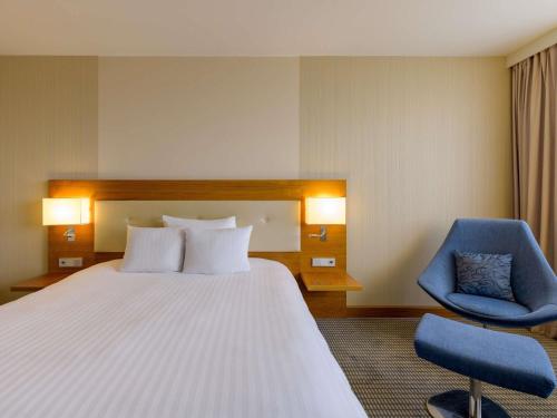 a hotel room with a bed and a blue chair at Mövenpick Hotel Geneva in Geneva
