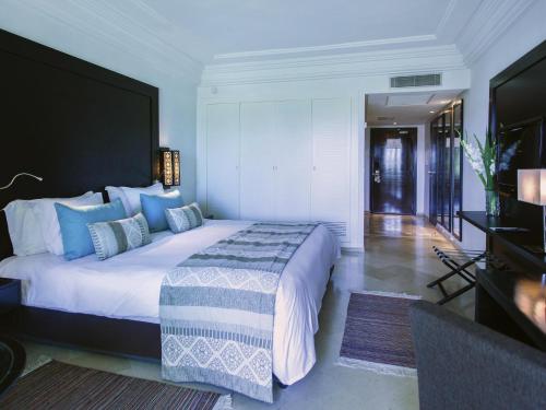 a bedroom with a large white bed with blue pillows at Mövenpick Hotel Gammarth Tunis in Gammarth