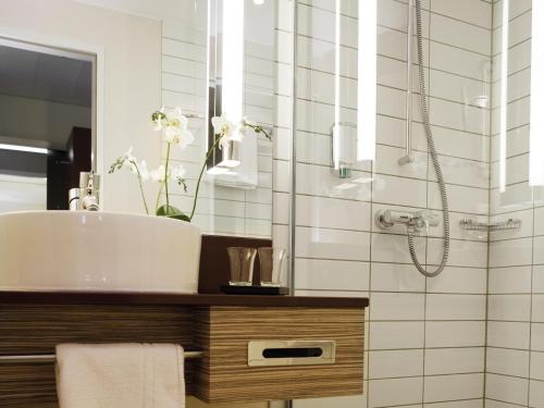 a bathroom with a sink and a shower at Mövenpick Hotel Frankfurt City Messe in Frankfurt/Main