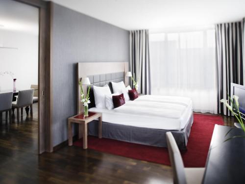 a bedroom with a white bed and a red rug at Mövenpick Hotel Stuttgart Airport in Stuttgart