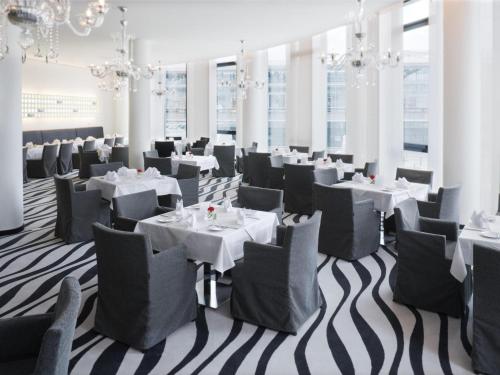 a dining room with white tables and chairs and chandeliers at Mövenpick Hotel Stuttgart Airport in Stuttgart