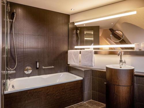 a bathroom with a bath tub and a sink at Mövenpick Hotel Hamburg City in Hamburg