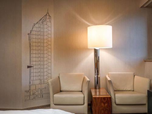 two chairs and a lamp in a hotel room at Mövenpick Hotel Hamburg City in Hamburg