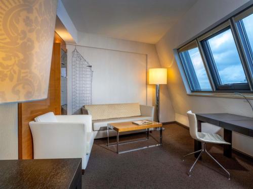 a small living room with a table and chairs at Mövenpick Hotel Hamburg City in Hamburg