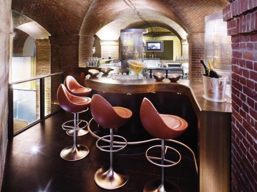a bar with three stools and a counter in a kitchen at Mövenpick Hotel Hamburg City in Hamburg