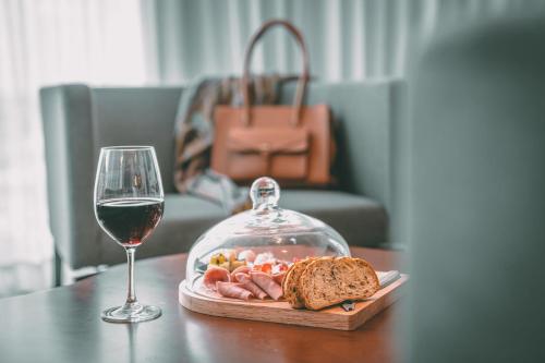 a glass of wine next to a plate of food and bread at Crowne Plaza Merida by IHG in Mérida