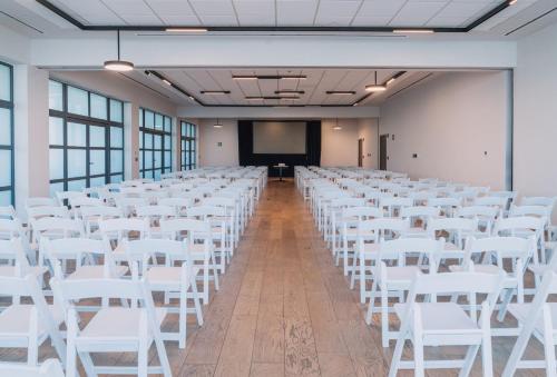 a large room with white chairs and a projection screen at Crowne Plaza Merida by IHG in Mérida