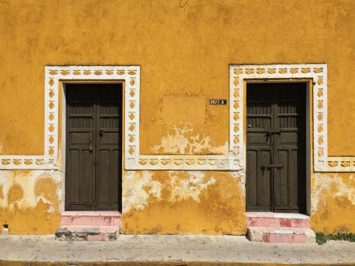 two doors on the side of a yellow building at Crowne Plaza Merida by IHG in Mérida