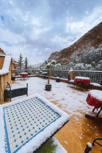 a snow covered patio with a pool in a yard at Auberge La Fibule Du Dades in Aït Idaïr