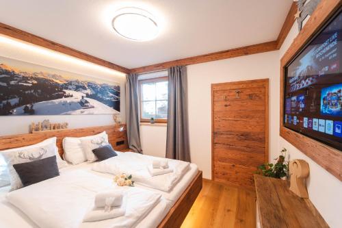 a bedroom with a large white bed with a television at TraumChalet mit Sauna in Kirchberg im Skigebiet Kitzbühel in Kirchberg in Tirol