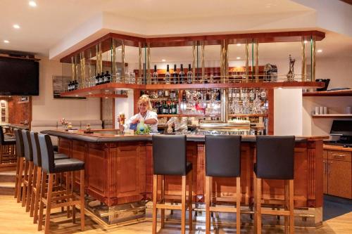 a woman sitting at a bar in a restaurant at NH Ingolstadt in Ingolstadt