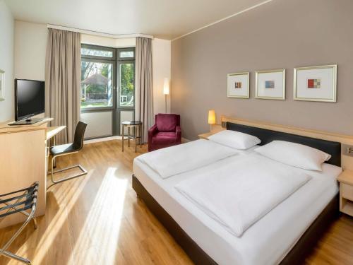 a bedroom with a large white bed and a chair at Mövenpick Hotel München-Airport in Hallbergmoos