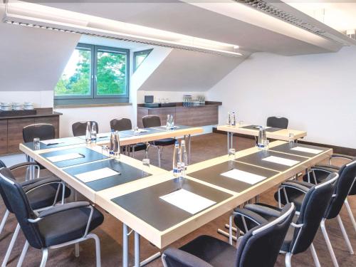 a conference room with a large table and chairs at Mövenpick Hotel München-Airport in Hallbergmoos