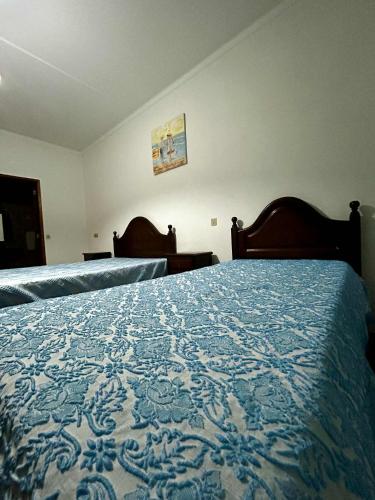 a bedroom with two beds with a blue and white blanket at Campinho Café Alojamento Local in Fátima