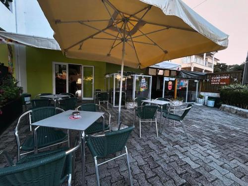 a patio with tables and chairs and an umbrella at Campinho Café Alojamento Local in Fátima
