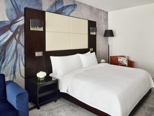 a bedroom with a large bed and a blue chair at Mövenpick Hotel Jumeirah Lakes Towers Dubai in Dubai