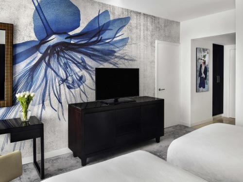 a bedroom with a tv and a painting on the wall at Mövenpick Hotel Jumeirah Lakes Towers Dubai in Dubai
