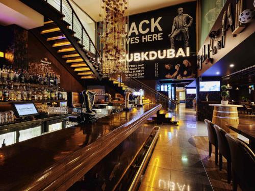 a bar with a wooden counter in a restaurant at Mövenpick Hotel Jumeirah Lakes Towers Dubai in Dubai