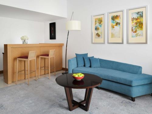 a living room with a blue couch and a table at Mövenpick Hotel Jumeirah Beach in Dubai
