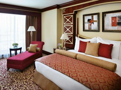 a hotel room with two beds and a chair at Mövenpick Hotel City Star Jeddah in Jeddah