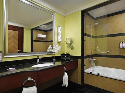 a bathroom with a sink and a tub and a mirror at Mövenpick Hotel City Star Jeddah in Jeddah