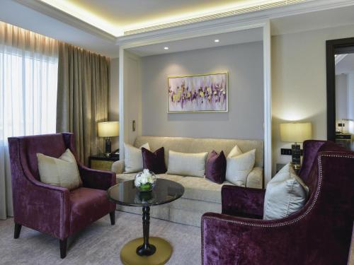 a living room with a couch and two chairs and a table at Mövenpick Hotel Bahrain in Manama
