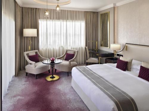 a hotel room with a bed and a table and chairs at Mövenpick Hotel Bahrain in Manama