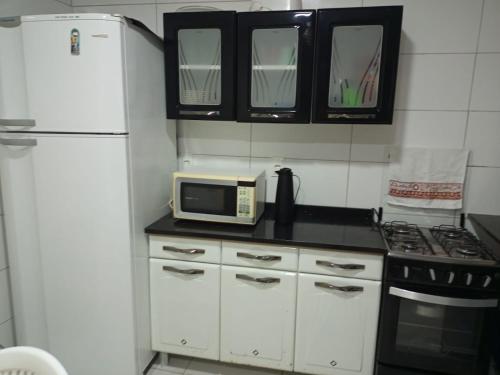 La cuisine est équipée d'un réfrigérateur blanc et d'un four micro-ondes. dans l'établissement Refúgio em Boipeba - Casa de Praia com Varanda e Conforto Tropical, à Cairu