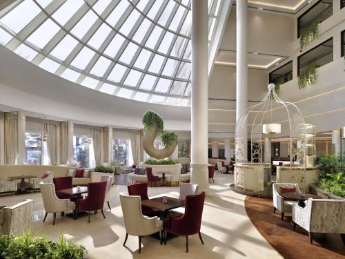 a restaurant with tables and chairs and a glass ceiling at Mövenpick Hotel Bahrain in Manama