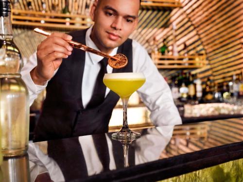 a man holding a stick in a drink at Mövenpick Hotel Bahrain in Manama