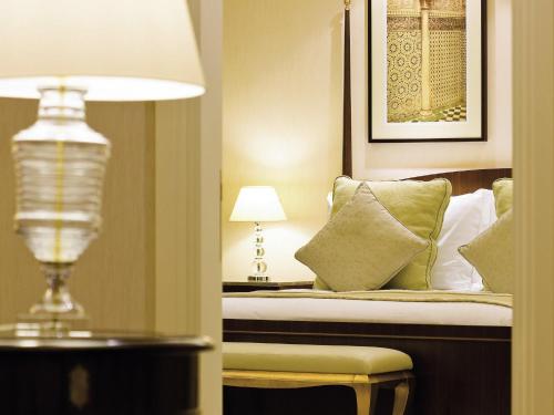 a bedroom with a bed with a lamp and pillows at Mövenpick Hotel Al Khobar in Al Khobar