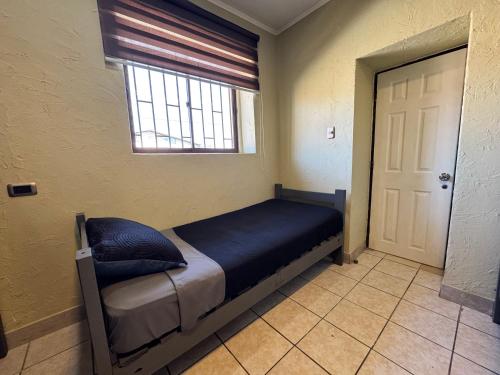 a bed in a room with a window and a door at Residencial Don Santiago in Talca