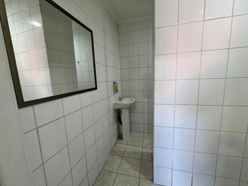 a white tiled bathroom with a mirror and a sink at Residencial Don Santiago in Talca