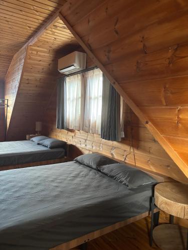 two beds in a room with wooden walls and windows at ISE Family Cabin in Ise