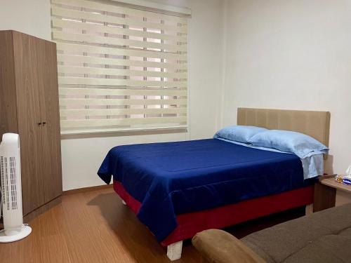 a bedroom with a blue bed and a window at Moderno departamento en Tula in Tula de Allende