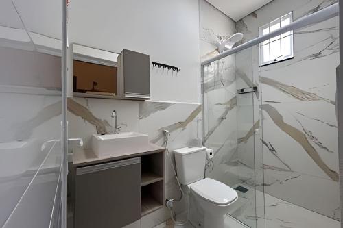 um banheiro branco com vaso sanitário e pia em Flats_Sabia em Uberlândia